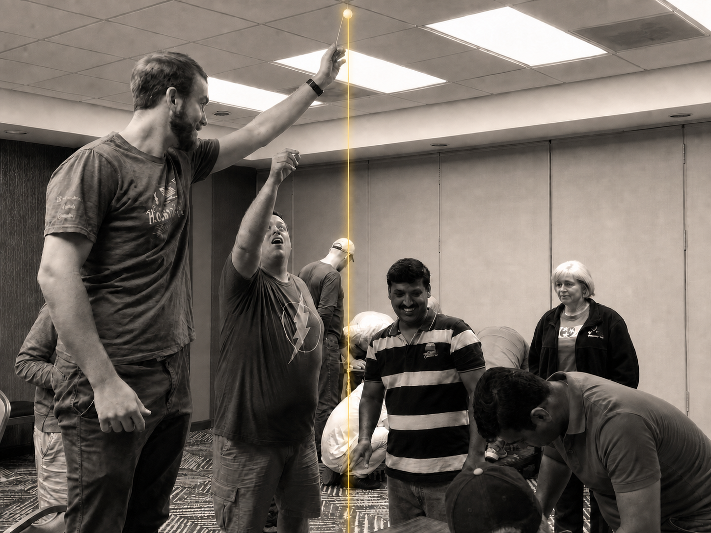 Workshop participants in warm monochrome working with glowing spaghetti and a marshmallow