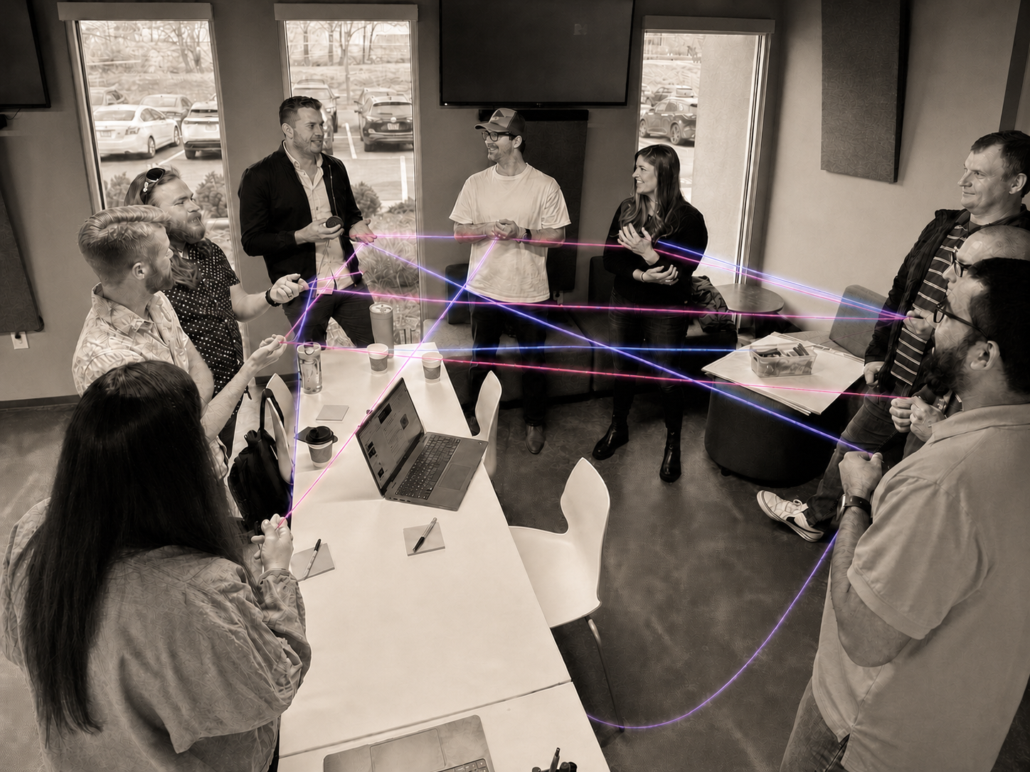 A group in warm monochrome taking part in an interactive yarn-network activity with illuminated strands